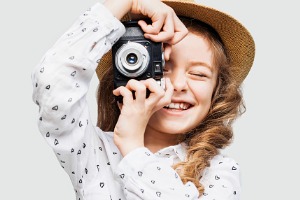 Young girl smiling taking a picture with a camera